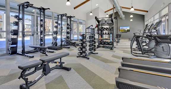 A gym with a variety of equipment including treadmills, weights, and exercise machines.