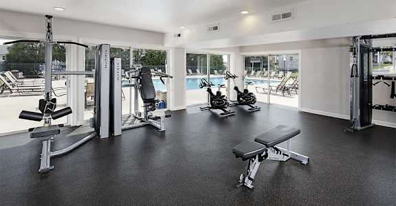a gym with exercise equipment and a pool in the background