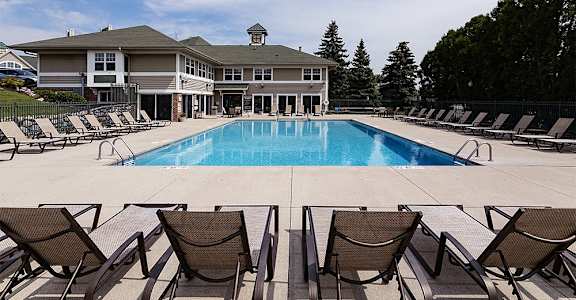 a swimming pool with chairs and a building in the background
