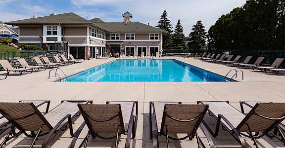 a swimming pool with chairs and a building in the background