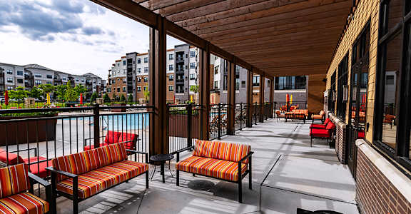A patio with wooden benches and tables overlooks a body of water.