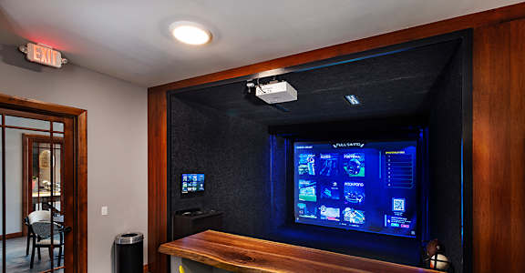 A room with a bar and a screen on the wall.