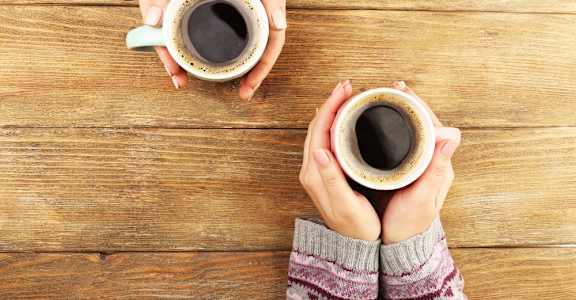 Two People Holding Cups of Coffee