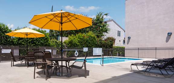 our apartments have a pool and a patio with chairs and umbrellas