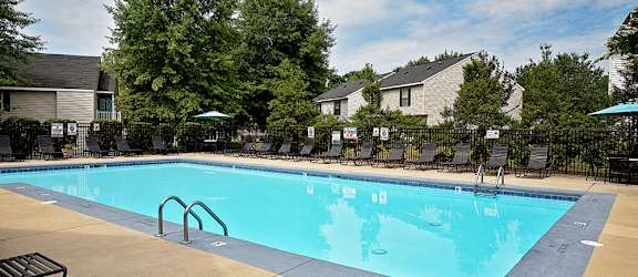 A large swimming pool surrounded by trees and lounge chairs.