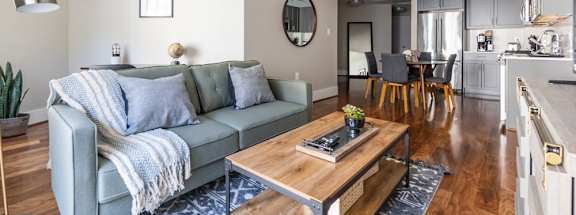 a living area with a couch coffee table and a kitchen in the background