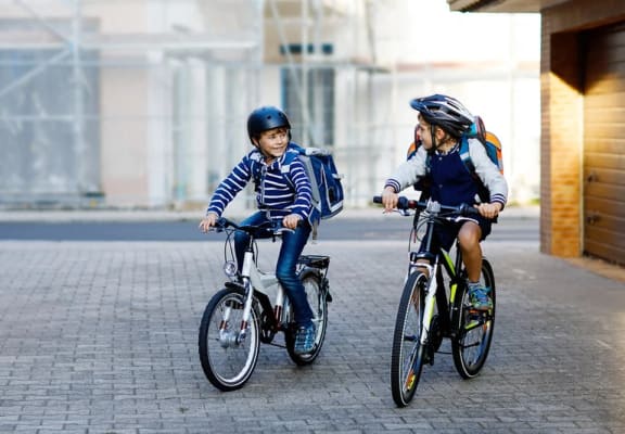 two kids riding bikes on a sidewalk