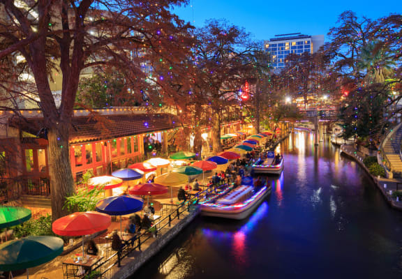 a city at night with colorful umbrellas and boats on the river