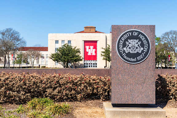 A sign for the University of Houston is in front of a building.
