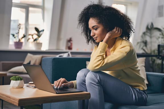 a woman sitting on a couch with a laptop on a coffee table