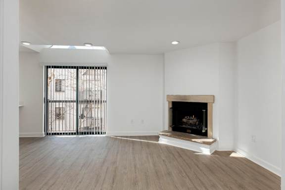 A large empty room with a fireplace and a sliding glass door.