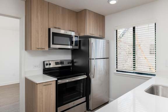 A kitchen with a black refrigerator, stove, and microwave.