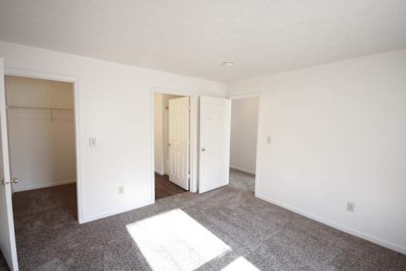 an empty bedroom with white walls and carpet