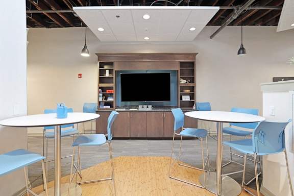 a seating area with tables and a tv in a break room