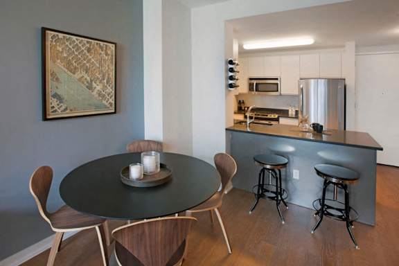A modern kitchen with a bar and a dining table with chairs at The Maximilian Apartments, New York