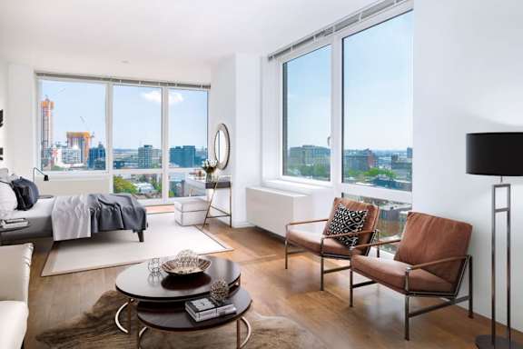 A modern living room with a view of the city at The Maximilian Apartments, Long Island City, NY
