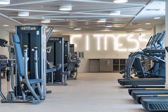 a gym with cardio equipment and a sign that says fitness