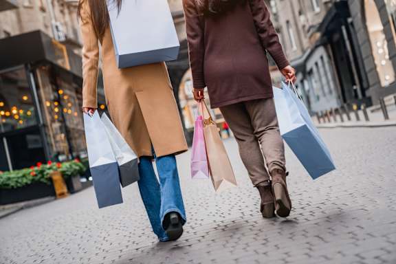 Two people walking down the street carrying shopping bags.