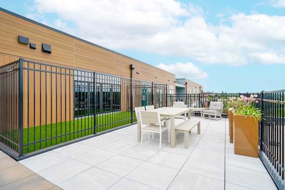 A patio with a table and chairs is surrounded by a black fence.