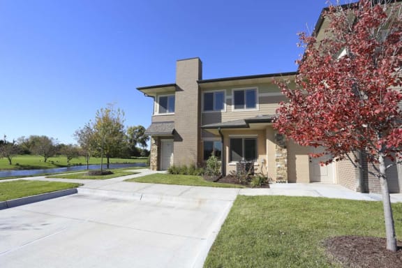 A house with a driveway and a tree with red leaves.