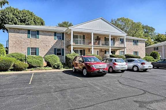 a parking lot in front of a brick apartment building