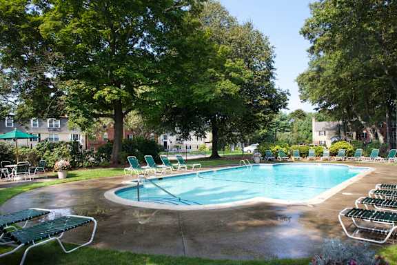 A swimming pool surrounded by sun loungers in a residential area.