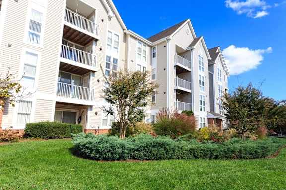 an exterior view of an apartment building with green grass and bushes at The Residences at the Manor Apartments, Frederick, 21702