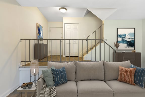 a living room with a couch and a staircase in the background at Copper and Quarry Village, Pikesville, MD, 21209