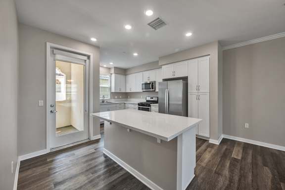 A modern kitchen with a white island and stainless steel appliances.