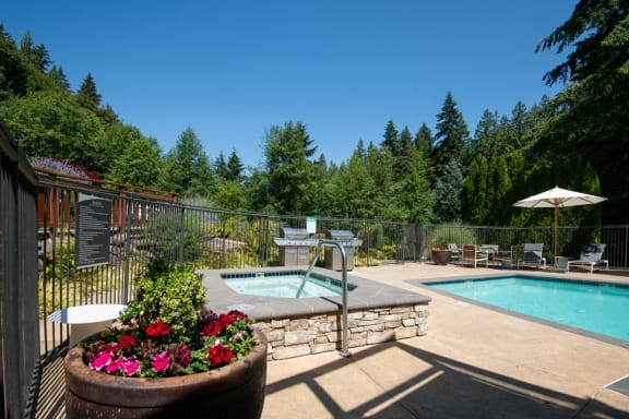 a resort style pool and hot tub in a backyard with trees at Lakemont Orchard, Issaquah, WA
