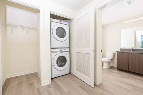 A white washer and dryer are stacked in a small laundry room at North Grove Apartments, Riverside