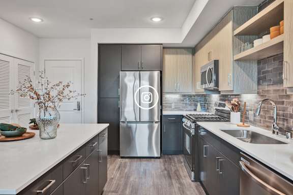 A modern kitchen with stainless steel appliances and wooden flooring.