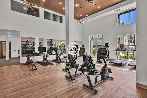 A gym with a variety of equipment including treadmills, stationary bikes, and weight machines.