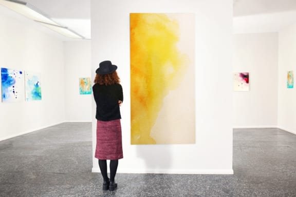 a woman looking at a large painting in an exhibition  at The Hemlock, Washington, 98103
