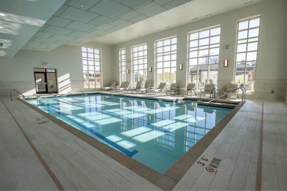 a large swimming pool in a room with chairs and windows
