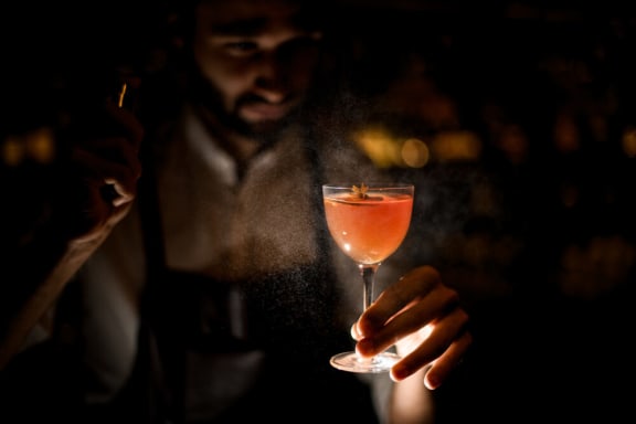 a bartender holding a cocktail in a glass