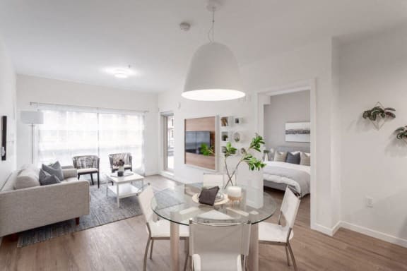 a living room with a glass table and a bedroom with a bed