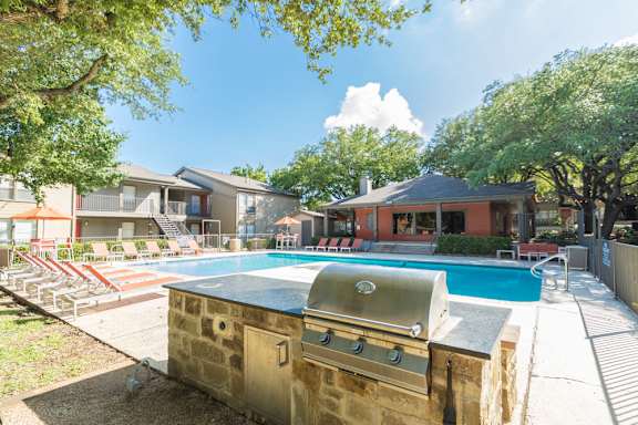 Pool area with outdoor grill and lounge seating at The Colony Apartments, Texas