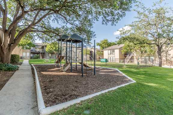 Community playground with climbing structure and slides at The Colony Apartments, Universal City, 78148