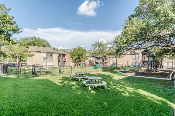 Courtyard with playground and picnic area surrounded by resident buildings at The Colony Apartments, Universal City, Texas