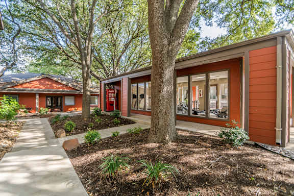 Exterior building with large windows and mature trees at The Colony Apartments, Texas