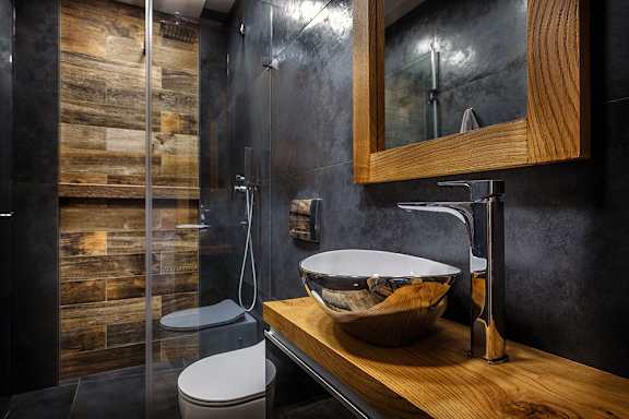 A modern bathroom with a wooden wall and a white toilet.