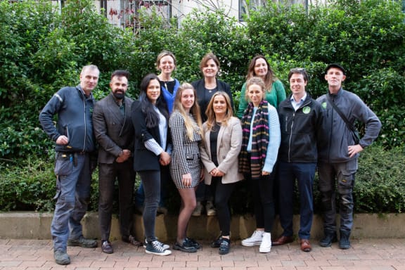 a group of people posing for a picture in front of some bushes