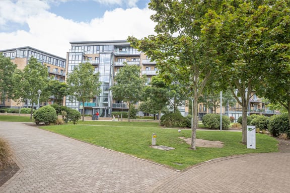 a park with grass and trees in front of a building