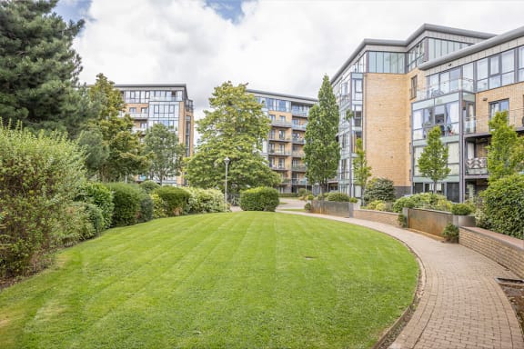 a courtyard with a lawn and trees in front of some buildings
