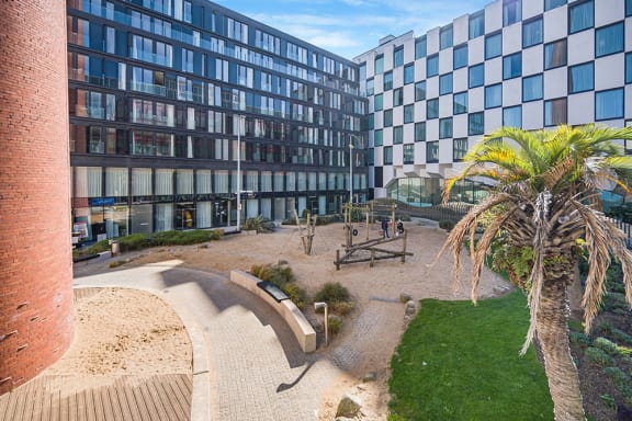 a park in front of a building with a palm tree
