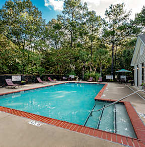 A pool surrounded by trees and a house.
