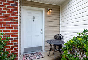 A white door with the number 111 on it is flanked by a brick wall and a white wall.