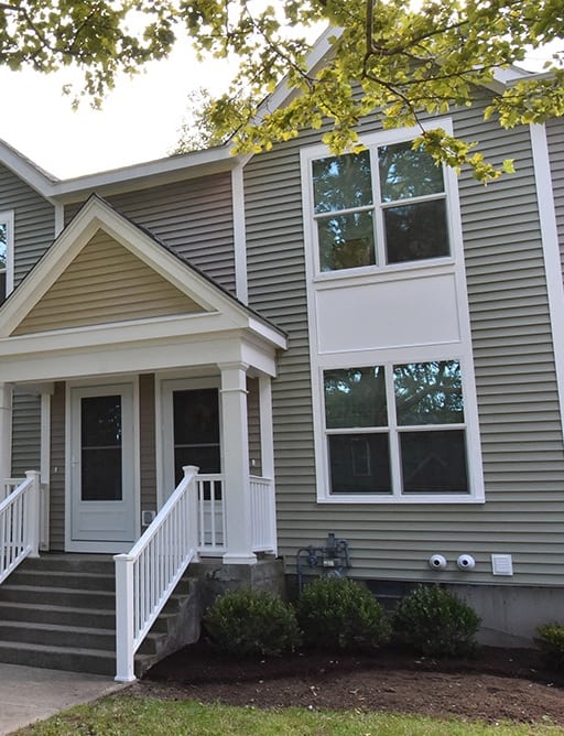 a gray house with white railings and a sidewalk