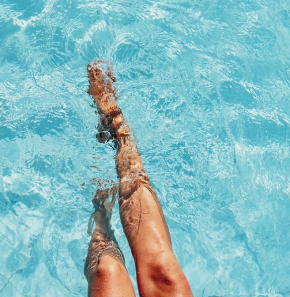 legs in a swimming pool with feet in the water